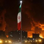 Foto: Bendera Iran berkibar saat api dan asap dari serangan Israel terhadap depot minyak Sharan membubung, menyusul serangan Israel terhadap Iran, di Teheran, Iran, 15 Juni 2025. (via REUTERS/Majid Asgaripour)